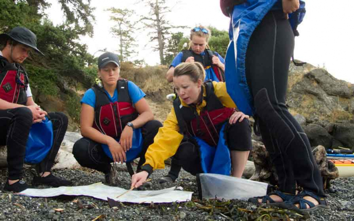 a group of people study a map on a kayaking course with outward bound
